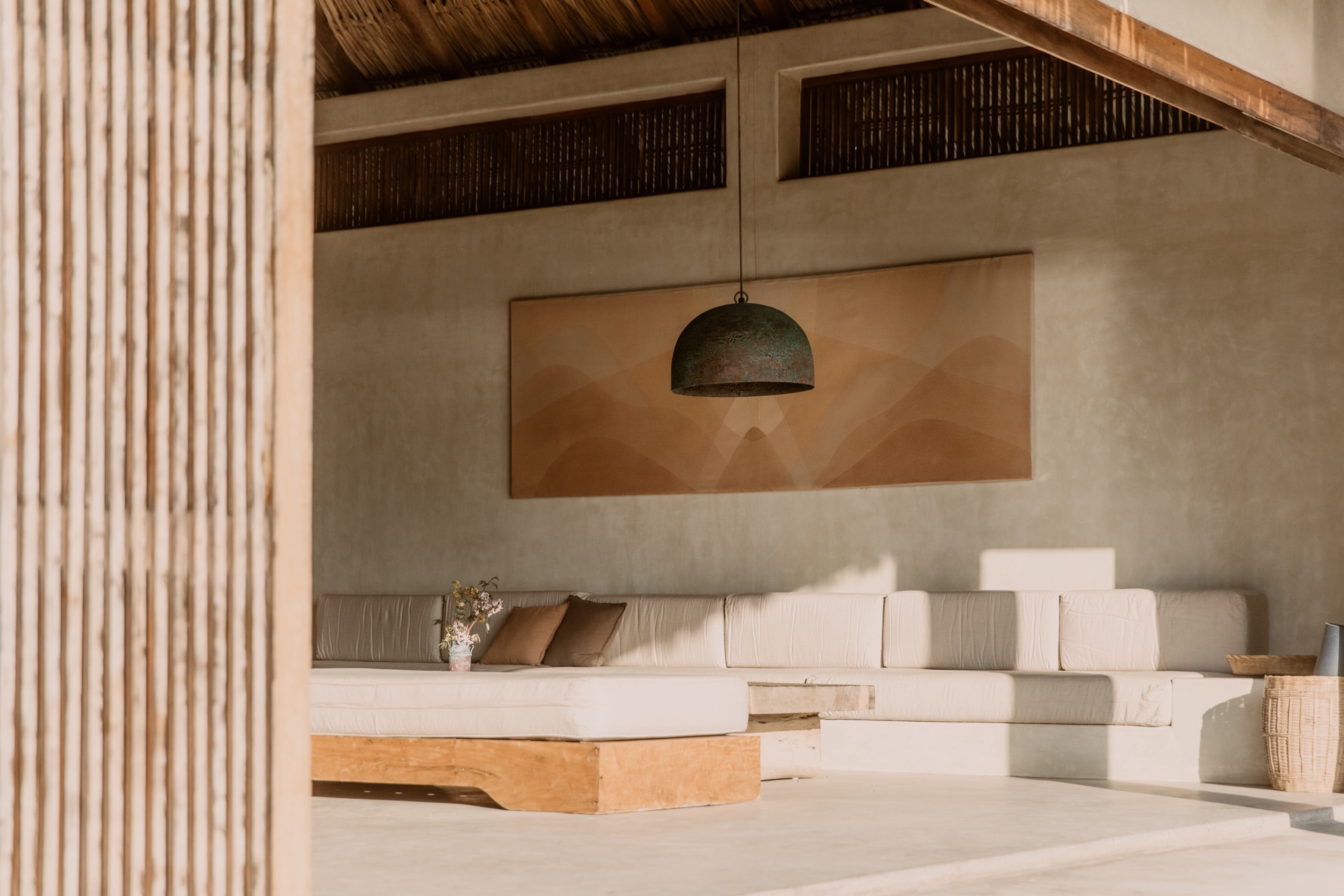 Palapa living room — verdigris pendant light and art over built-in sofa