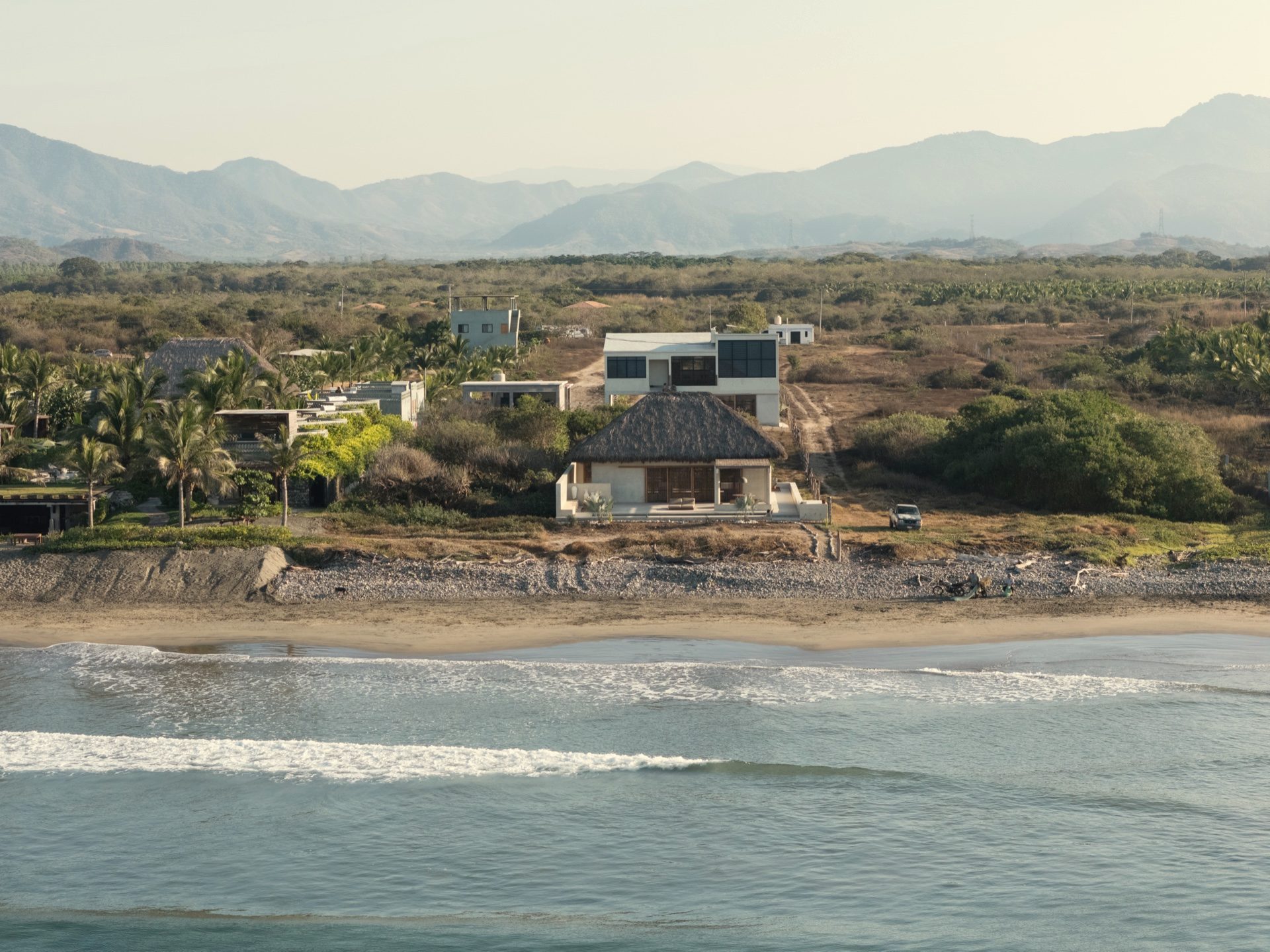 Aerial view of Casa Kona — beachfront compound with palapa, pool and Sierra Madre mountains